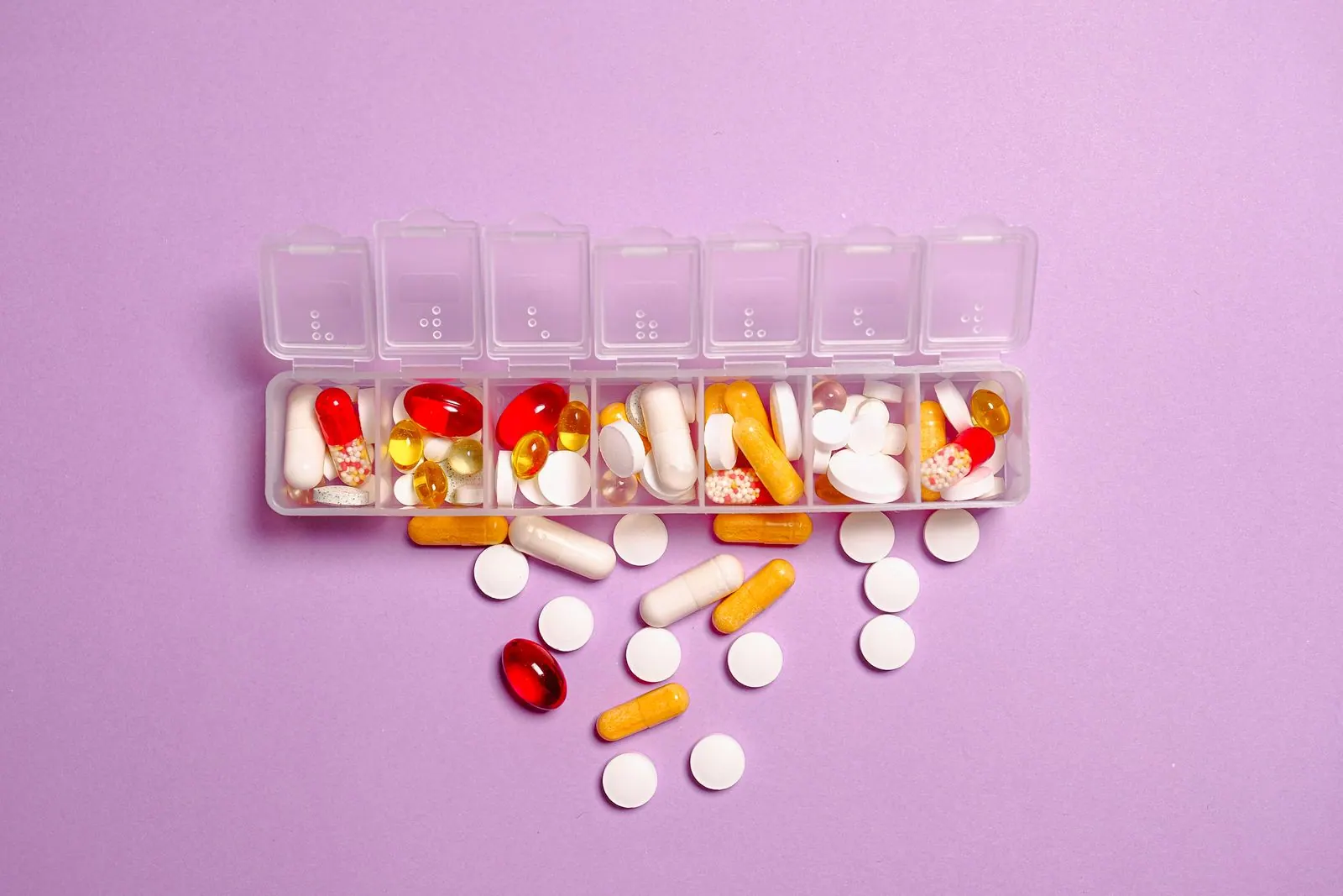 Medicine tablets and capsules arranged beside a pill organizer
