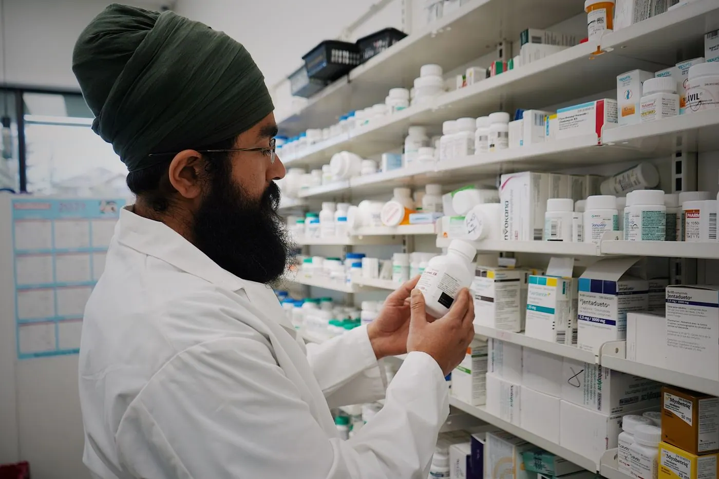 Pharmacist reviewing medicine stock on pharmacy shelves